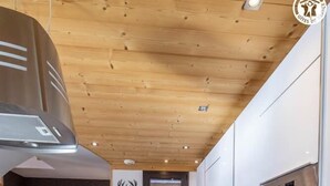 Una cocina moderna con armarios blancos, un horno de acero inoxidable y techo de madera.