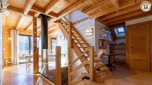 Un interior de madera con una escalera, una chimenea y un comedor.
