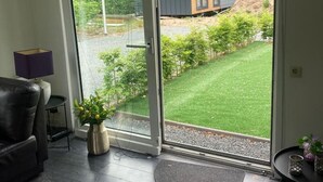 Ein modernes Wohnzimmer mit einer Schiebeglastür, die zu einem Garten führt.