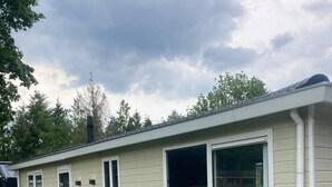 Einbungalow mit einem großen Schiebeglastür, einer kleinen Veranda und einem gepflegten Rasen.