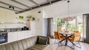 Een moderne keuken met witte kasten, een inbouwoven en een eethoek met een tafel en stoelen.
