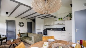 Een moderne woonkamer met een bank, eettafel en een keuken op de achtergrond.