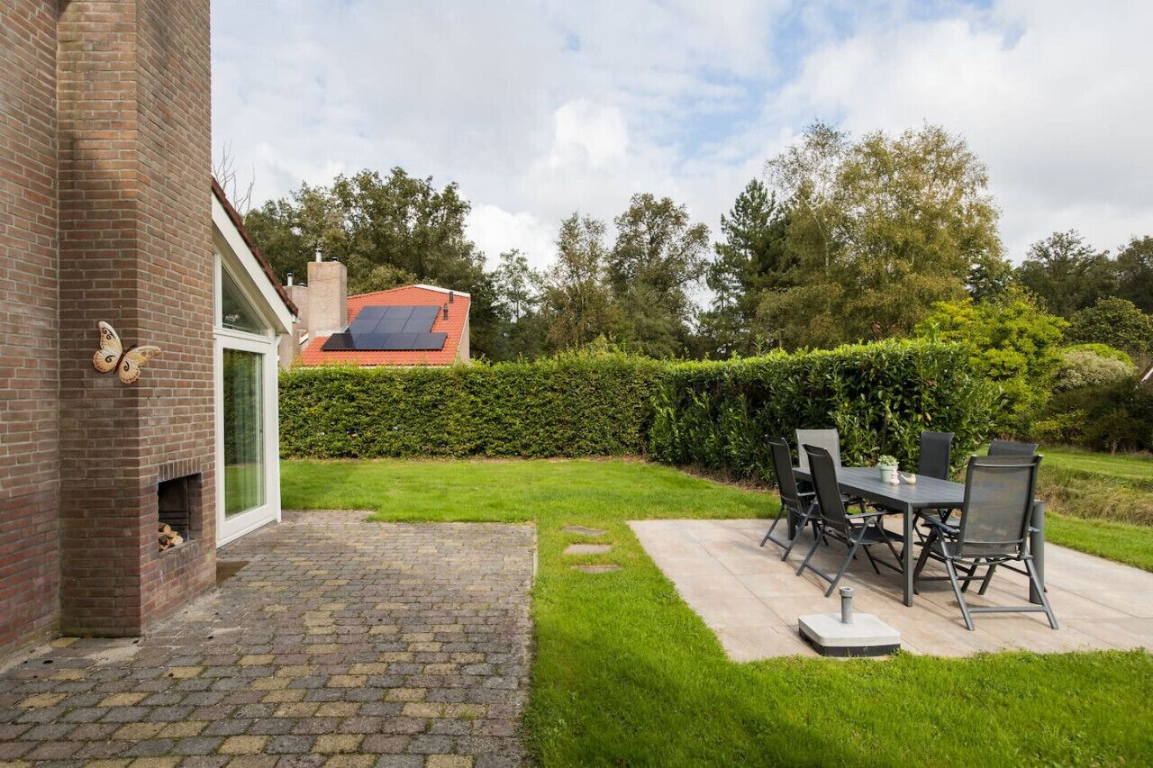A patio with a table and chairs, a brick wall, and a solar panel on a building in the background.