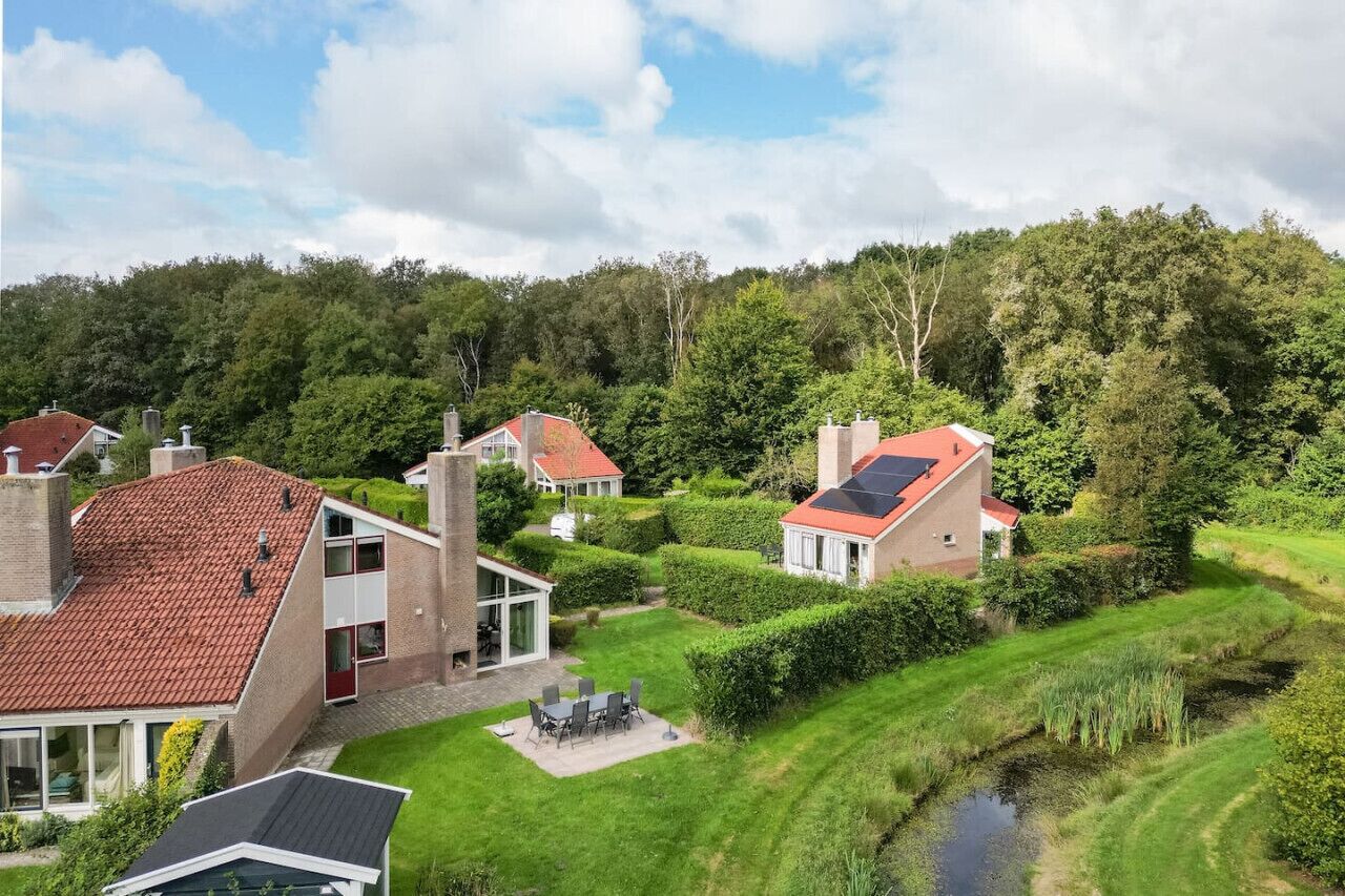 A residential area with modern houses, a small pond, and lush greenery.