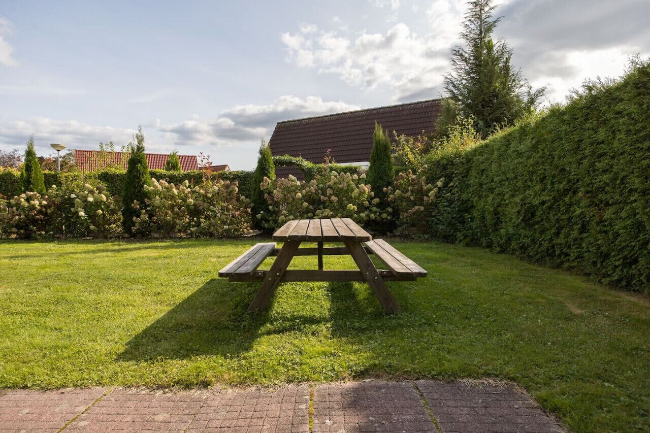 A picnic table in a grassy area with a building in the background.