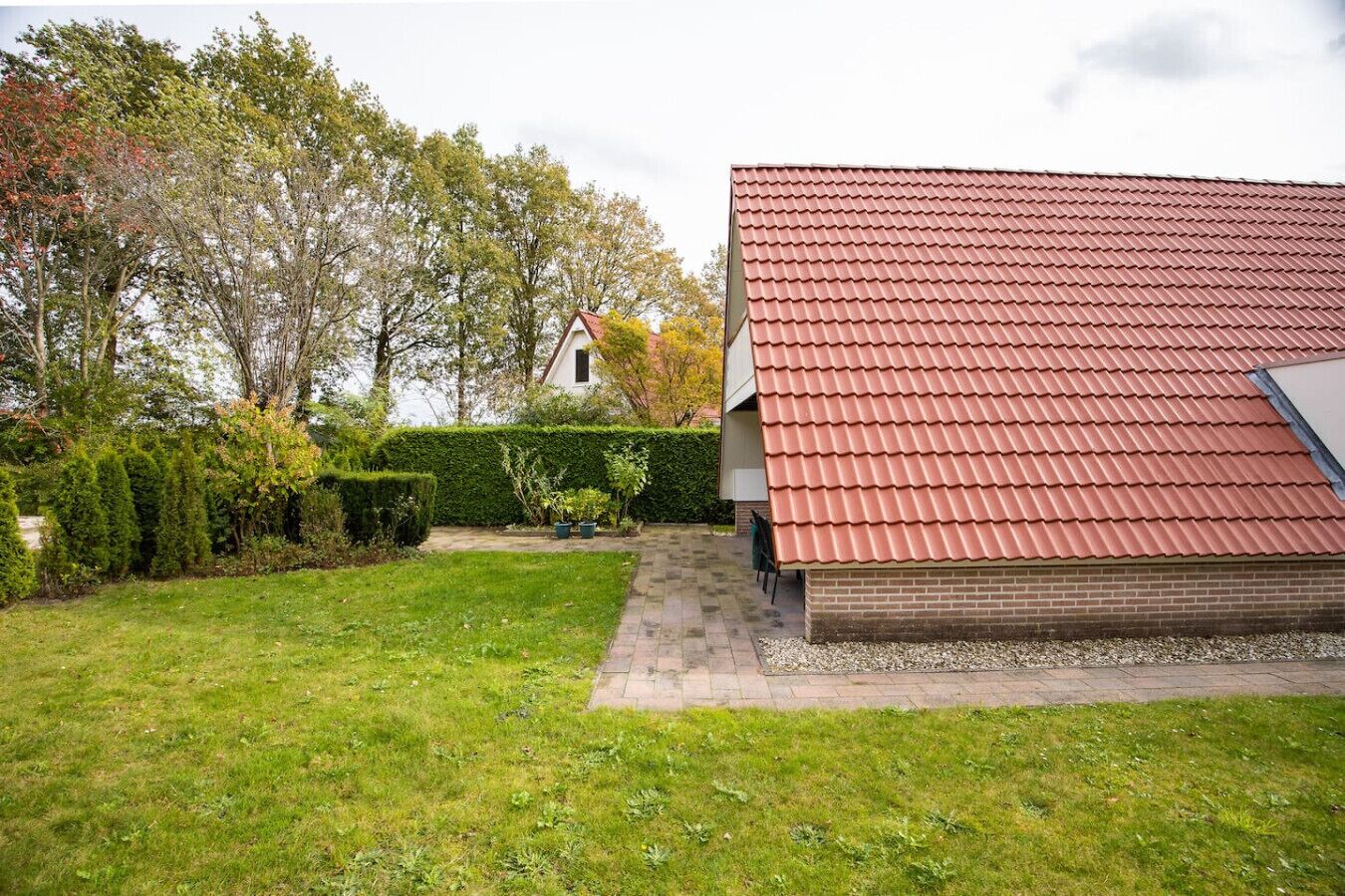 A house with a red tiled roof, a brick exterior, and a well-maintained lawn.