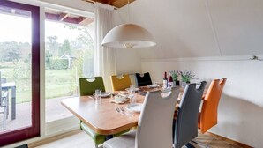 Un espace repas comprenant une table en bois, des chaises et un luminaire suspendu.