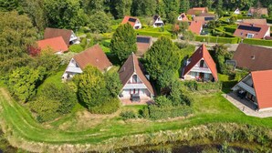 Un quartier résidentiel où les maisons se distinguent par leurs toits recouverts de tuiles rouges et leurs murs blancs, le tout étant entouré d’une végétation luxuriante et d’arbres.