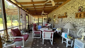A covered patio area with a table and chairs, a ceiling fan, and a brick wall. - Beautiful brick home w/ large porch and 3 bedrooms (Bowman)