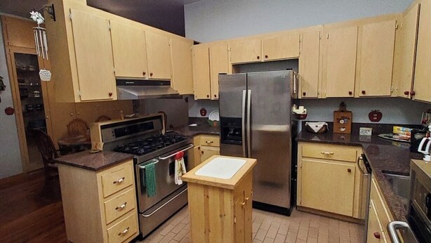 A compact kitchen with wooden cabinets, a stainless steel refrigerator, and a gas stove. - Beautiful brick home w/ large porch and 3 bedrooms (Bowman)