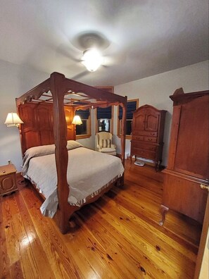 A four-poster bed with a wooden canopy, a wooden wardrobe, and a chair in a room with wooden flooring and a ceiling light. - Beautiful brick home w/ large porch and 3 bedrooms (Bowman)