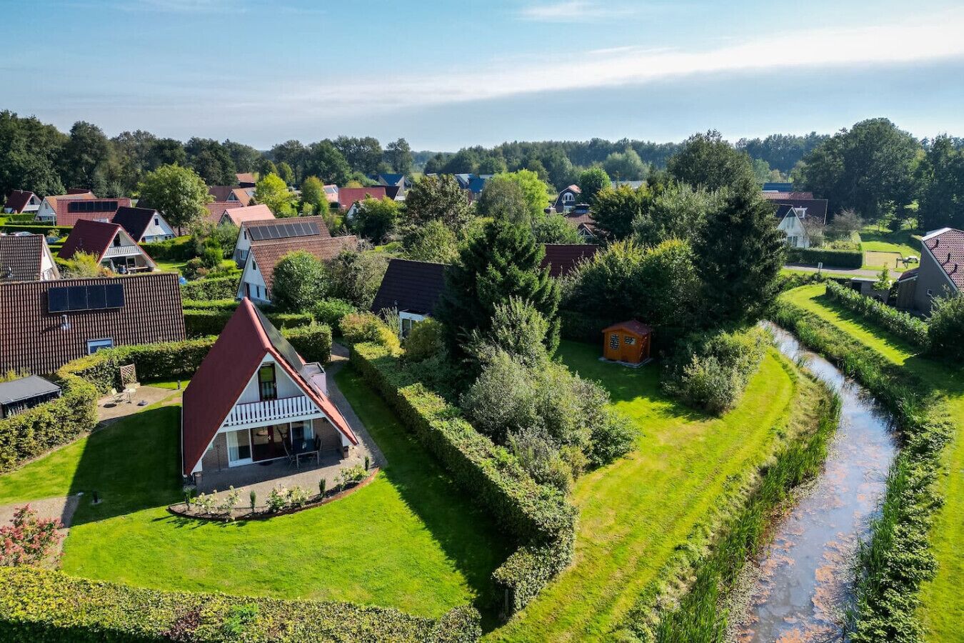 Een woonwijk met huizen, een rivier en een verzorgd gazon.