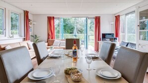 A dining area with a table set for four, a bottle of wine, and a bowl of snacks. - Pheasant I Beautiful Quiet Holiday Home with Garden (Zwiggelte)