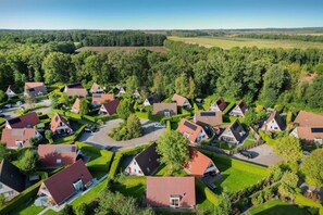Un quartier résidentiel où les maisons sont disposées selon un plan en forme de grille, entouré de champs verdoyants et d’arbres.