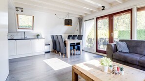 A modern kitchen with white cabinets, a dining area with a table and chairs, and a living room with a sofa and a coffee table.