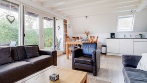 A spacious living area with a sofa, armchair, and coffee table. A dining table with chairs is visible in the background. - Tufted Duck I Vacation Home with Modern Interior (Zwiggelte)