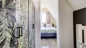 Une chambre à coucher avec un lit, une armoire et une vue sur une autre pièce.