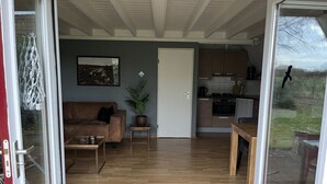 A living room with a sofa, coffee table, and a potted plant. - Dunnock I Home with Fireplace in Surrounding Garden (Zwiggelte)