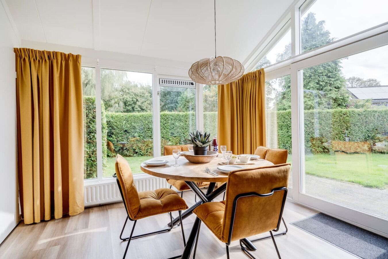 A dining area with a round table, four chairs, and a hanging light fixture.