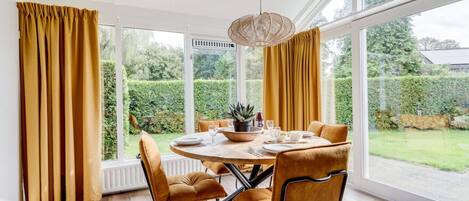 A dining area with a round table, four chairs, and a hanging light fixture.