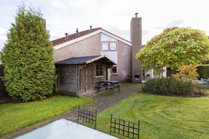A rustic building with a brick exterior, a wooden shed, and a picnic table in the yard. - Red Kite I Stylish Bungalow with Private Garden (Zwiggelte)