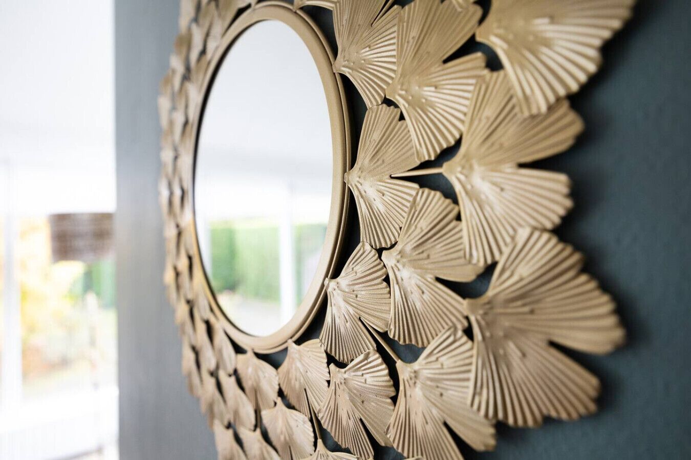 A wall-mounted mirror with a decorative, leaf-like frame.