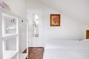 A bedroom with a bed, a wardrobe, a door with a mirror, and a painting on the wall. - Red Kite I Stylish Bungalow with Private Garden (Zwiggelte)