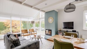 A spacious living area with a fireplace, a dining table set for two, and a comfortable seating arrangement.