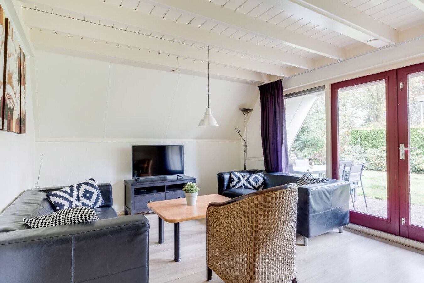 A modern living room with a TV, two sofas, a coffee table, and a wicker chair.