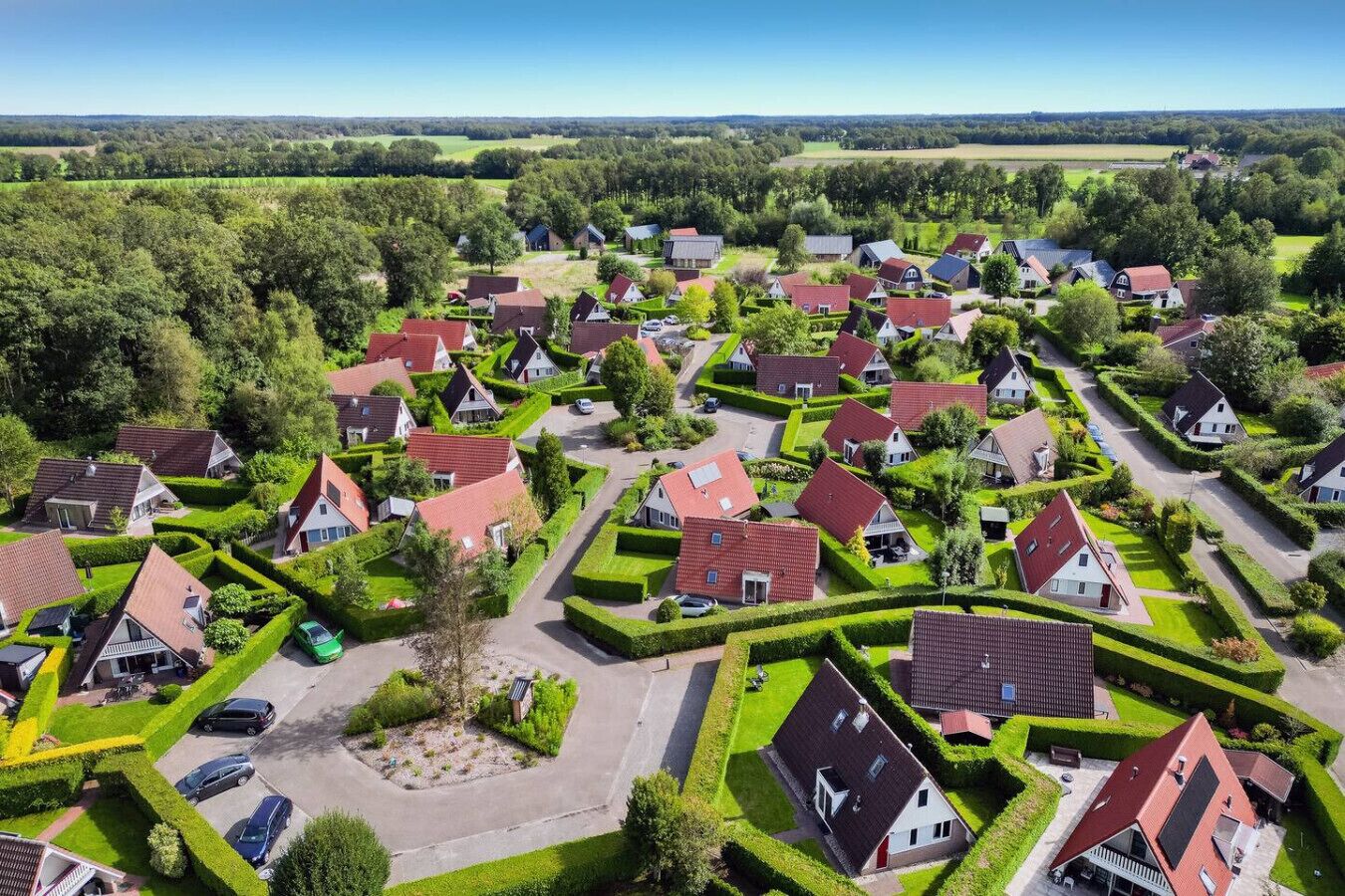 An aerial view of a residential area with houses, roads, and green spaces.