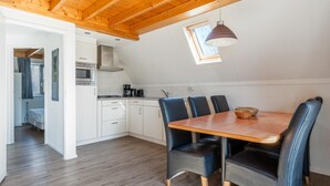 Una cocina moderna con armarios blancos, una mesa de comedor de madera y sillas azules.