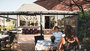 An outdoor cafe with tables and chairs, a 'Welcome' sign, and a 'Open' sign.