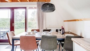 A dining area with a wooden ceiling, a table set for four, and a view of the outdoors. - ChiffChaff I Cottage Overlooking Spacious Garden (Zwiggelte)