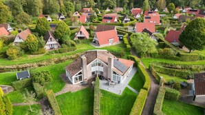 Ett bostadsområde med hus som har röda tak, omgivet av välskötta trädgårdar och häckar.