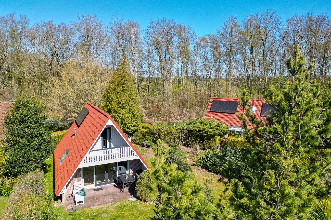Een huis met een rood dak, een balkon en een kleine tuin.