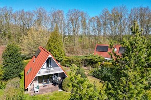 A house with a red roof, a balcony, and a small garden area.