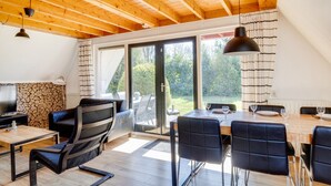 A modern living room with a wooden ceiling, a fireplace, a TV, and a dining area with a table and chairs. - Nightingale I Holiday Home with Lovely Garden (Zwiggelte)