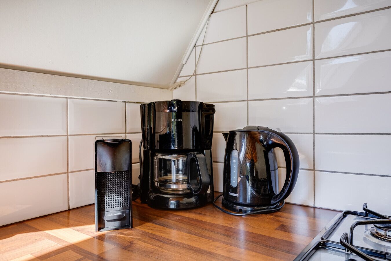 Een keuken met een koffiezetapparaat, een waterkoker en een fornuis.
