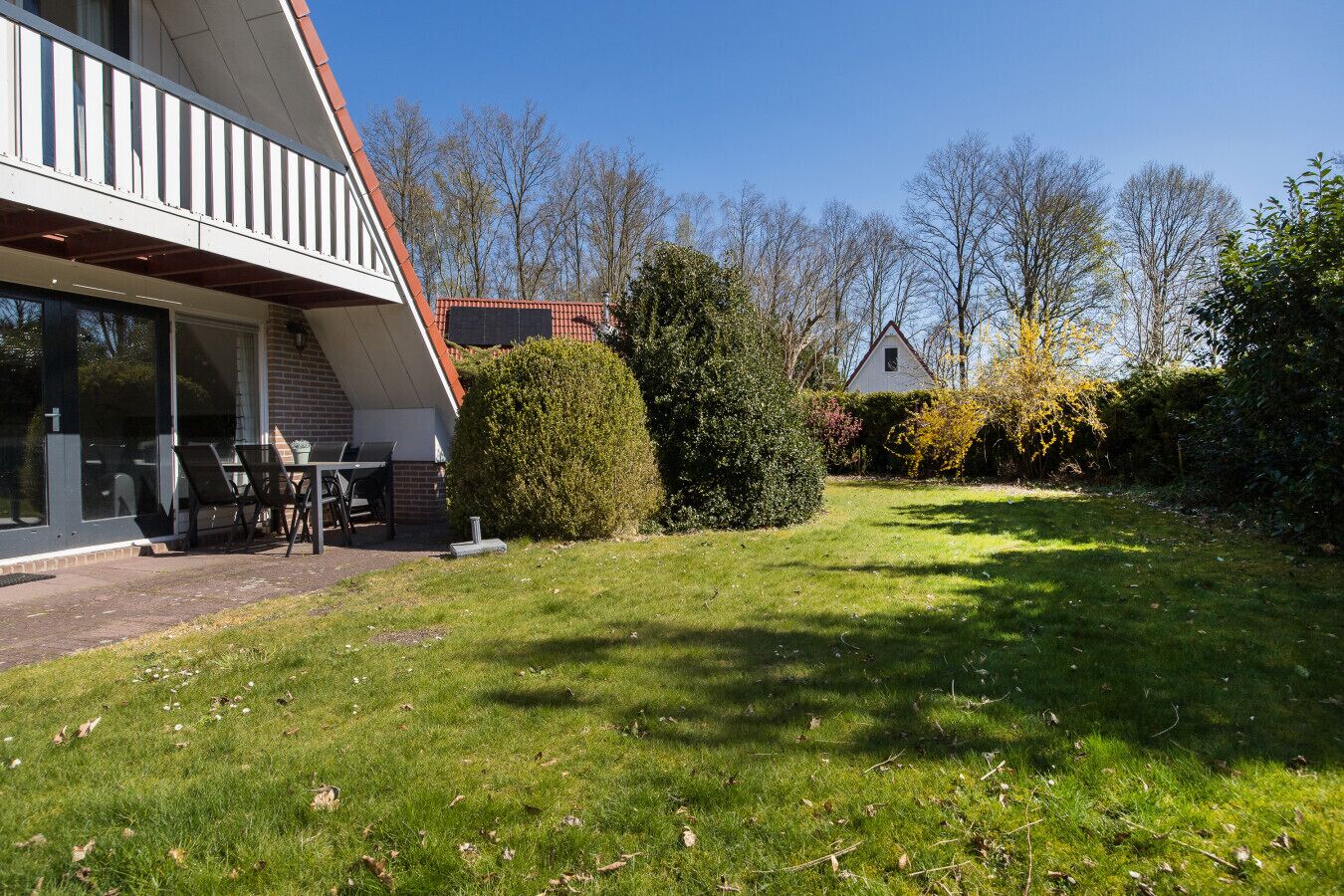 Une maison moderne dotée d’un patio, d’une grande fenêtre et d’une pelouse bien entretenue.