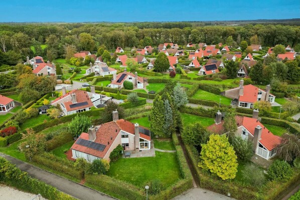 Een woonwijk met huizen met rode daken, omringd door keurig onderhouden tuinen en hagen.