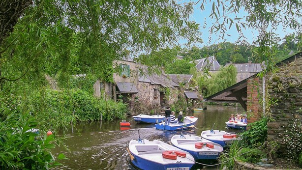 Ein schmaler Kanal mit anlegenden Booten, umgeben von üppiger Vegetation und historischen Gebäuden.