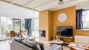 Una sala de estar moderna con un sofá, sillones, un televisor y una chimenea.