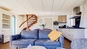 A modern living room with a sofa, coffee table, and a staircase leading to an upper level. - Fieldfare I Home with Fine Garden (Zwiggelte)