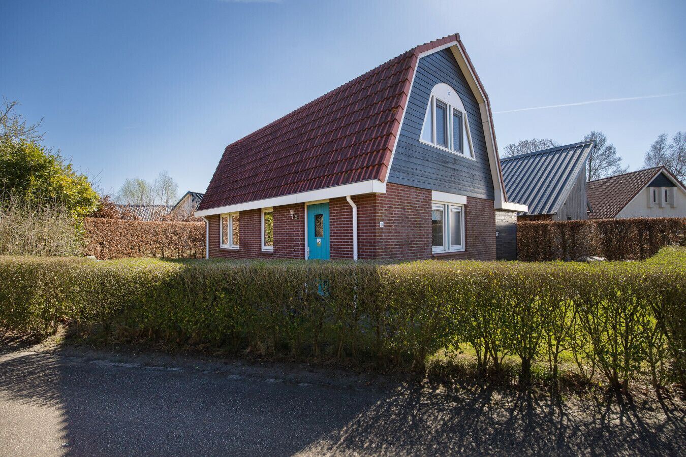 A two-story house with a steeply pitched roof, a blue door, and a brick facade.