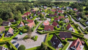 Een vogelvluchtperspectief van een woongebied met huizen, wegen en groene ruimtes.