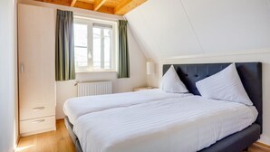 A bedroom with two beds, a window with curtains, a radiator, and a wooden ceiling. - Lovely House I View Garden and Farmland (Zwiggelte)