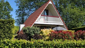 A small, triangular-roofed building with a balcony, surrounded by lush greenery and trees. - Lovely House I View Garden and Farmland (Zwiggelte)