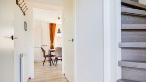 A hallway with a wooden floor, a dining area with two chairs and a table, and a staircase with wooden steps. - Cuckoo I Modern Home with Private Garden (Zwiggelte)