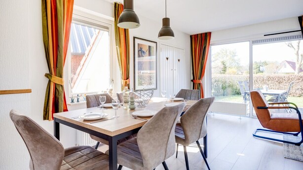 A dining area with a table set for four, chairs, and a view of the outdoors. - Cuckoo I Modern Home with Private Garden (Zwiggelte)
