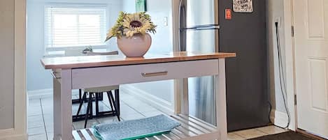 Una cocina con ventilador de techo, refrigerador y una mesa de comedor con sillas.